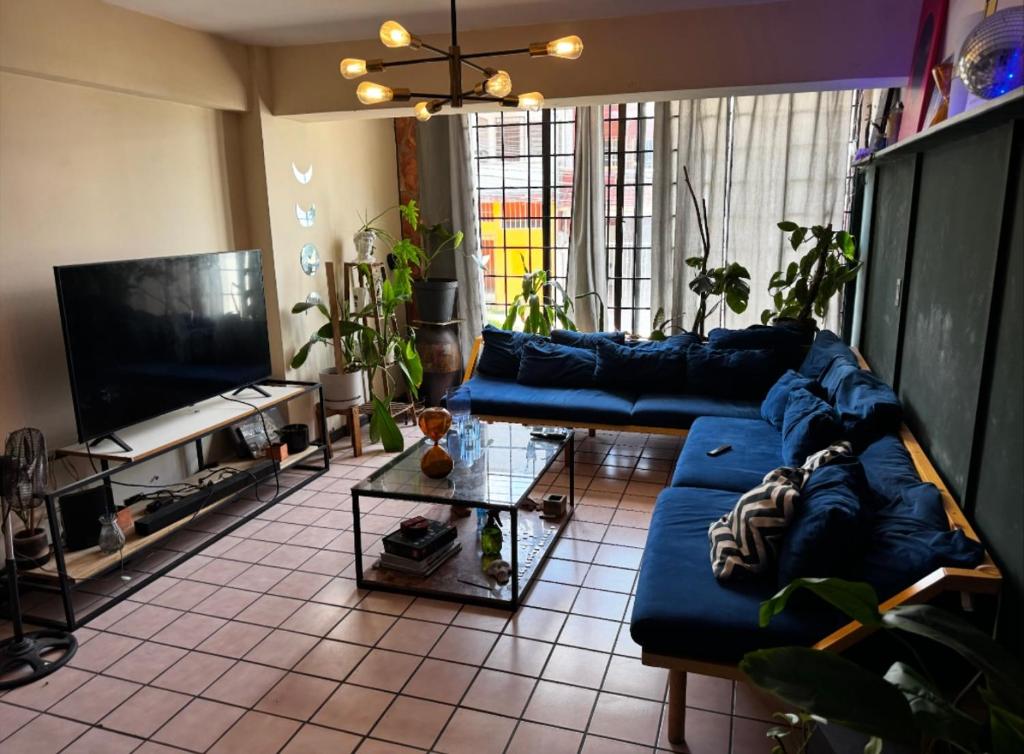 een woonkamer met een blauwe bank en een tv bij Habitación en Depto chic compartido in Villahermosa