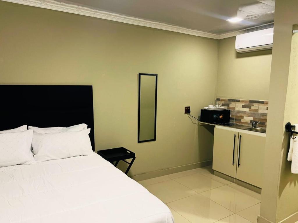 a bedroom with a white bed and a kitchen at PholaBnB in Pongola