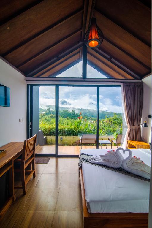 a bedroom with a bed and a large window at Alam Munduk Cabin in Munduk
