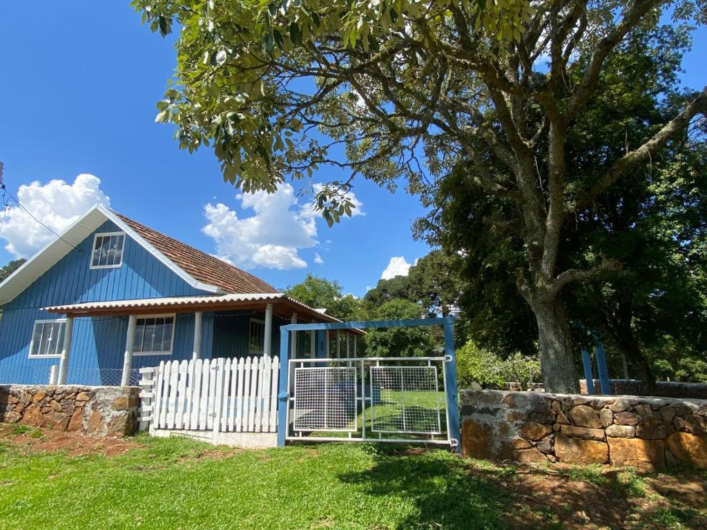 una casa blu con una recinzione e un albero di Chácara Leopoldo Bairro a Lages