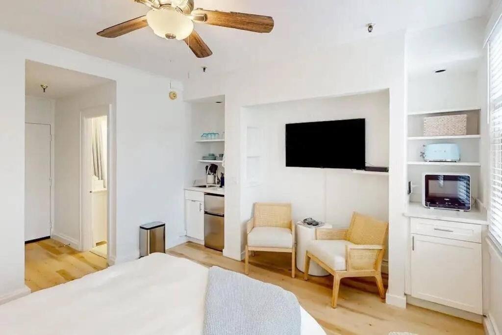 a white bedroom with a bed and a flat screen tv at Palm Beach Condo 5 Mins to Beach Heated Pool in Palm Beach