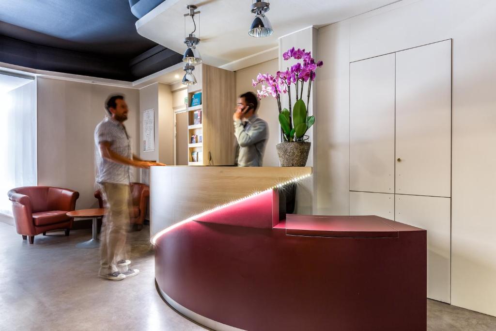 two people standing in a lobby with a red bench at Grand Hôtel Lille in Lille