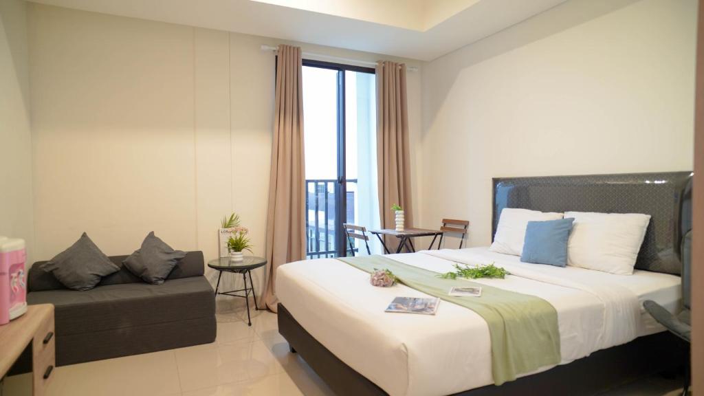 ジャカルタにあるSpacious and Homey Studio at Cleon Park Apartment By Travelioの大きなベッドとソファのあるホテルの部屋