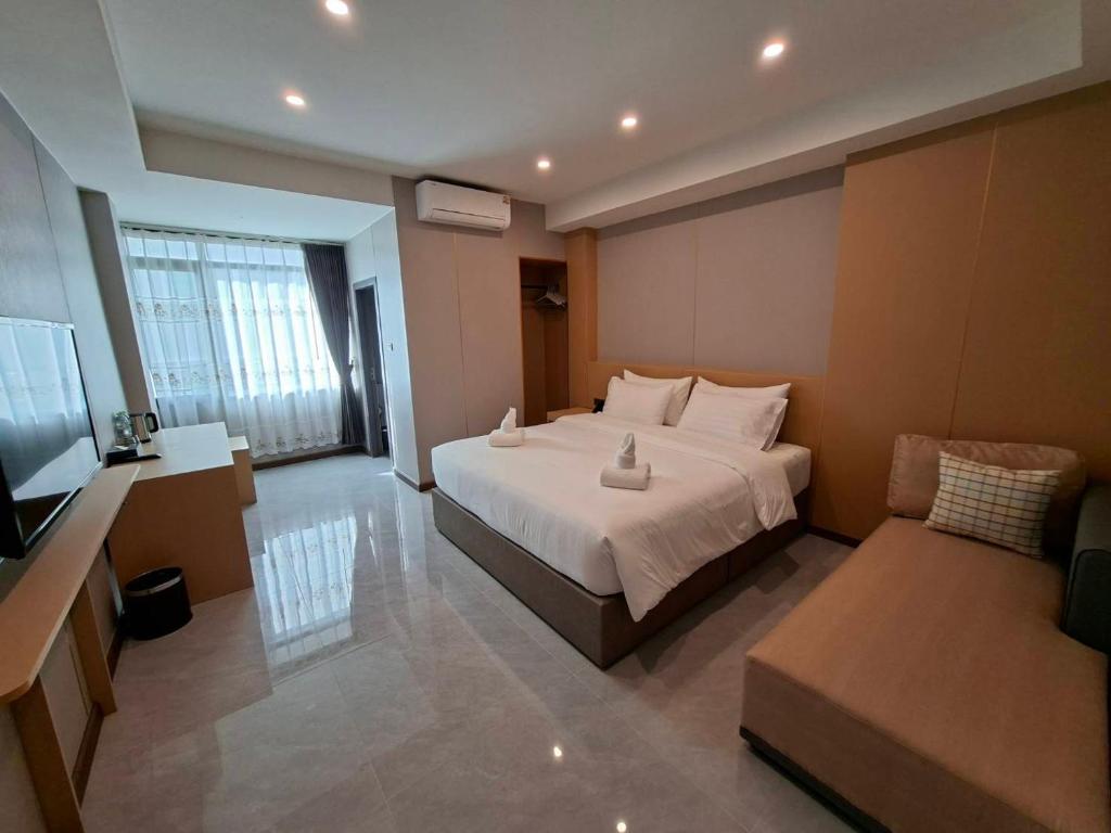 een grote slaapkamer met een bed en een bank bij Velin Pattaya Hotel in Ban Nong Chaeng