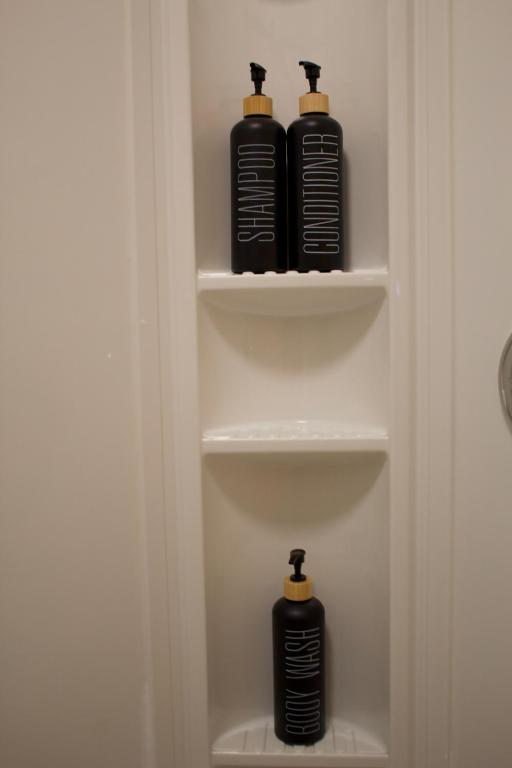 two black shampoo bottles sitting on shelves in a bathroom at Studio - Cozy Downtown Hideaway in Sudbury