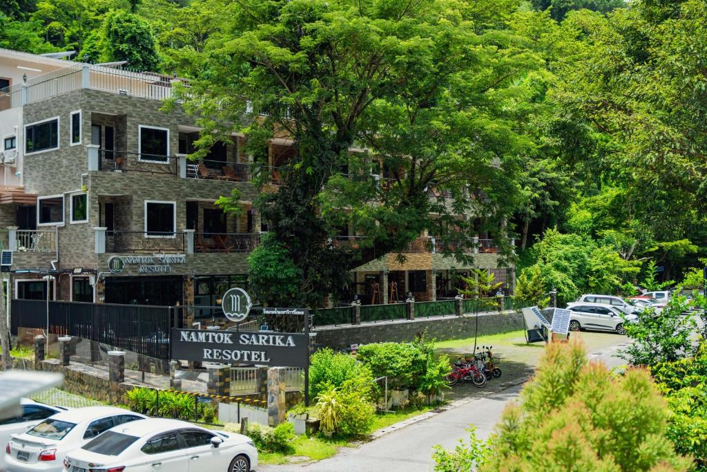 Namtok Sarika Resotel في ناخون نايوك: شارع فيه سيارات تقف امام مبنى