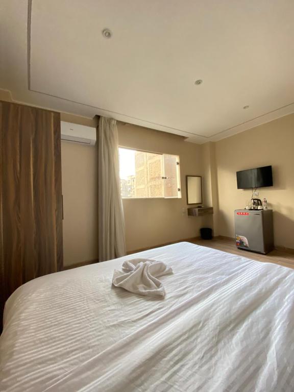 a white bed in a room with a window at Good Nights Pyramids Hotel in Cairo