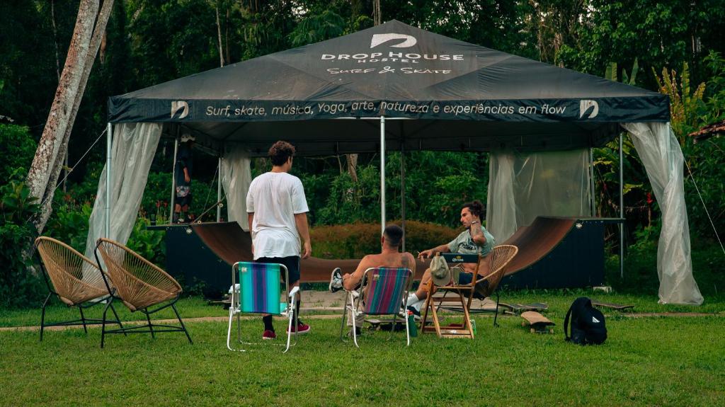 a group of people sitting in chairs under an umbrella at Drop House Hostel in Ubatuba