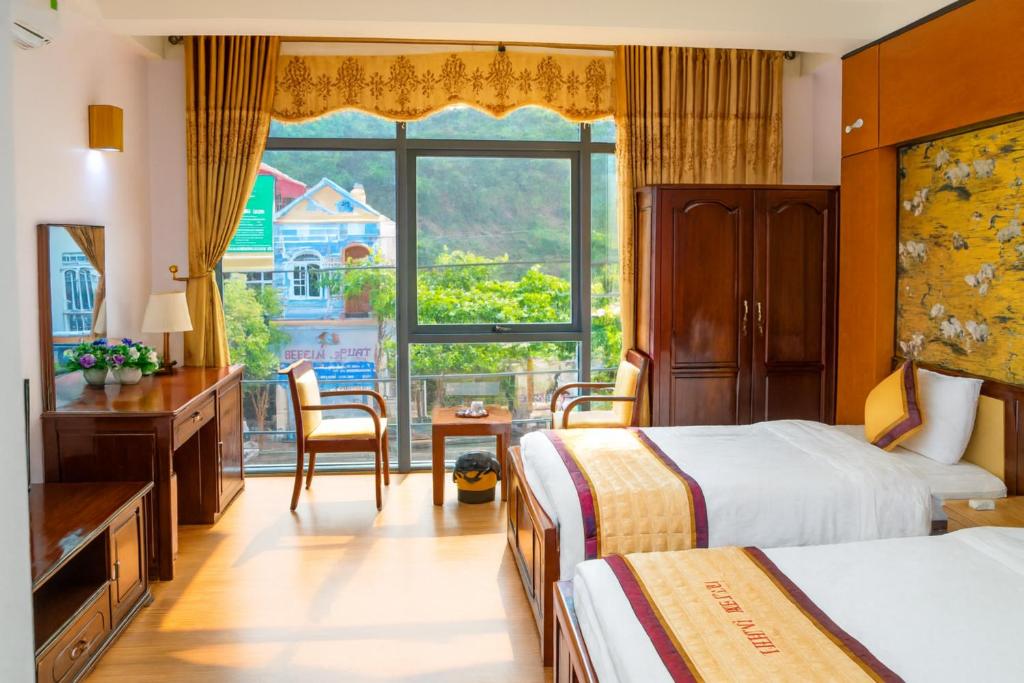 a hotel room with two beds and a large window at Hải Vân Hotel Điện Biên in Diện Biên Phủ