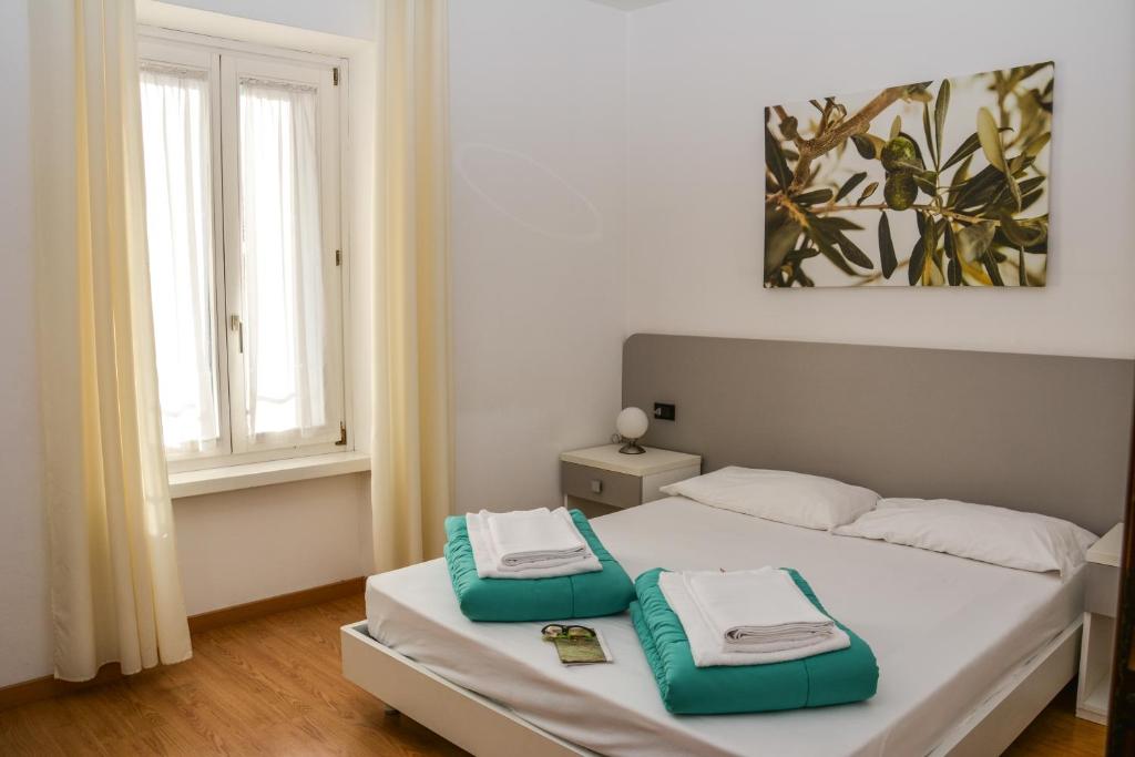 - une chambre avec un lit et des serviettes vertes et blanches dans l'établissement Stella Sport Apartments, à Nago-Torbole