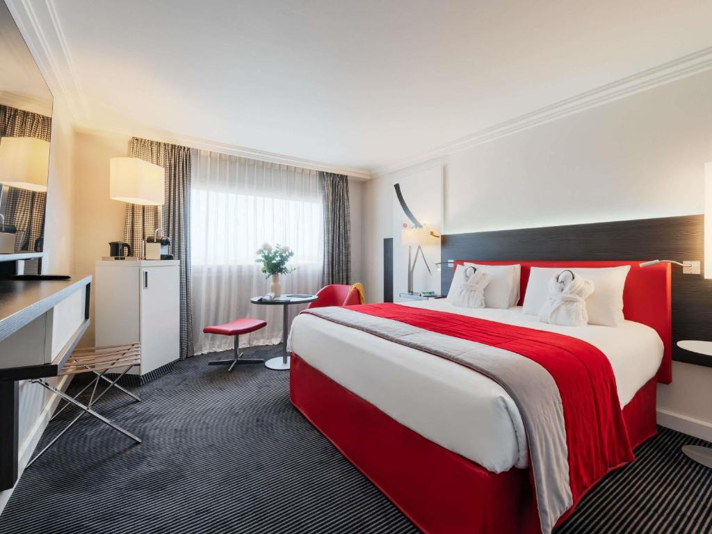 a hotel room with a large bed and a desk at Mercure Paris CDG Airport & Convention in Roissy-en-France