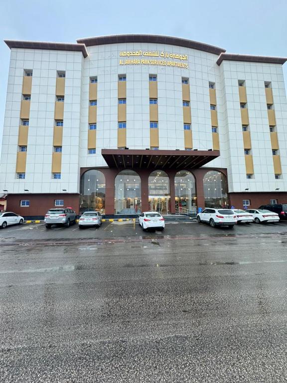 الجوهرة بارك 4 للشقق المخدومة في حفر الباطن: مبنى كبير به سيارات متوقفة في موقف السيارات