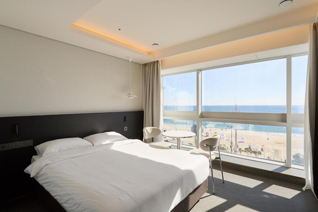 Un dormitorio con una cama y vistas a la playa. en Cov Stay Haeundae, en Busan