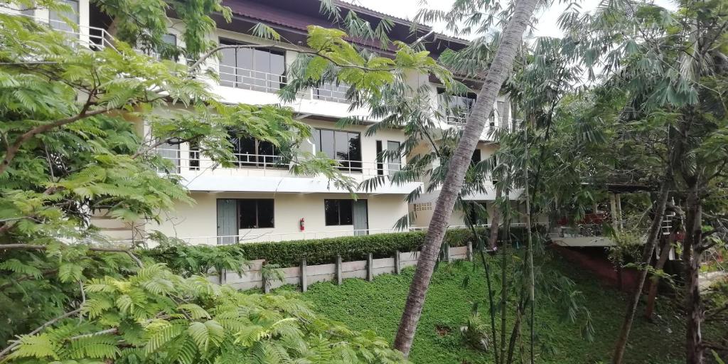 a white building with trees in front of it at Baan-kawkaew-kata in Ban Karon
