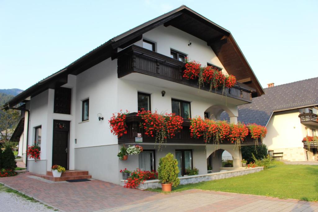 ein weißes Gebäude mit roten Blumen auf den Balkonen in der Unterkunft Apartma Maržič in Kranjska Gora