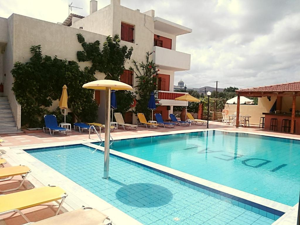 uma piscina com cadeiras e um guarda-sol ao lado de um edifício em Ideal Hotel em Kokkíni Khánion