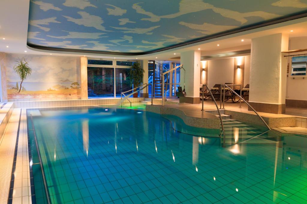 une grande piscine avec un plafond peint de nuages dans l'établissement Kurhotel Sonnenhof, à Bad Füssing