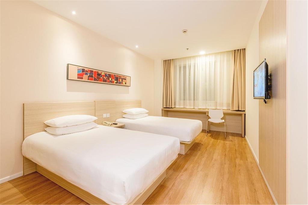 a hotel room with two beds and a flat screen tv at Hanting Hotel Fuzhou Wuyizhong Road in Fuzhou