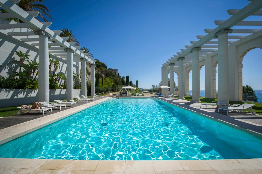 a swimming pool with white columns and blue water at Luxury Apartment Palais Maeterlinck in Nice