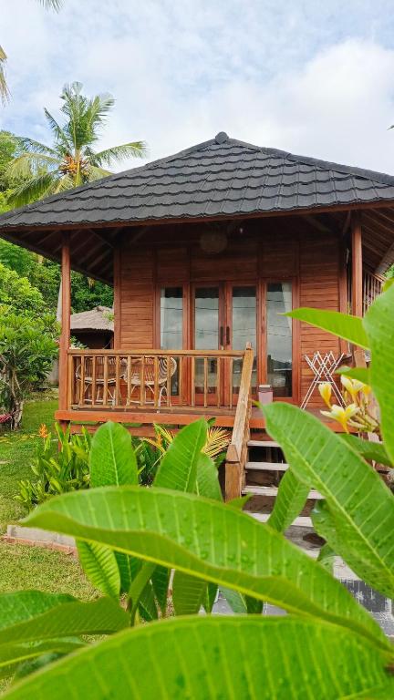 a small wooden house with a porch and some plants at Yellow Coco Gili Gede in Gili Gede