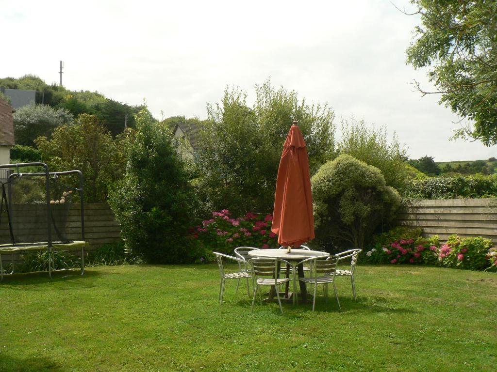 a table with an umbrella and chairs in a yard at Les Costils in Saint-Laurent-sur-Mer
