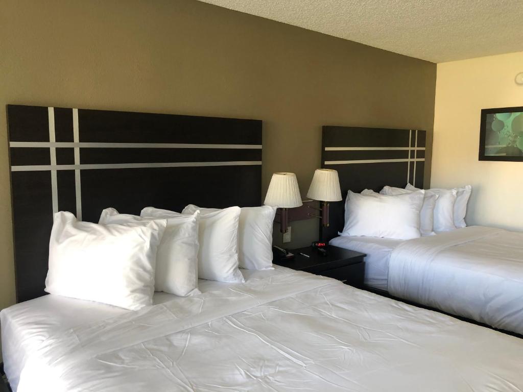 zwei Betten in einem Hotelzimmer mit weißen Kissen in der Unterkunft Green Palms Extended Stay in Kissimmee