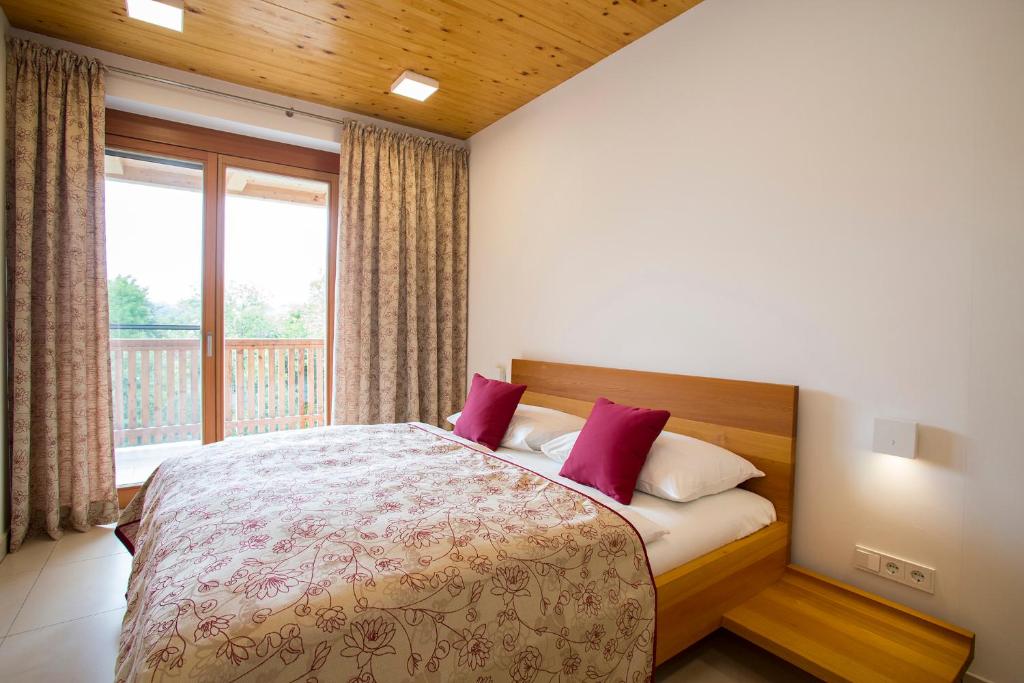 Schlafzimmer mit einem Bett mit roten Kissen und einem Fenster in der Unterkunft Moor-Rosl Apartmenthotel in Gamlitz