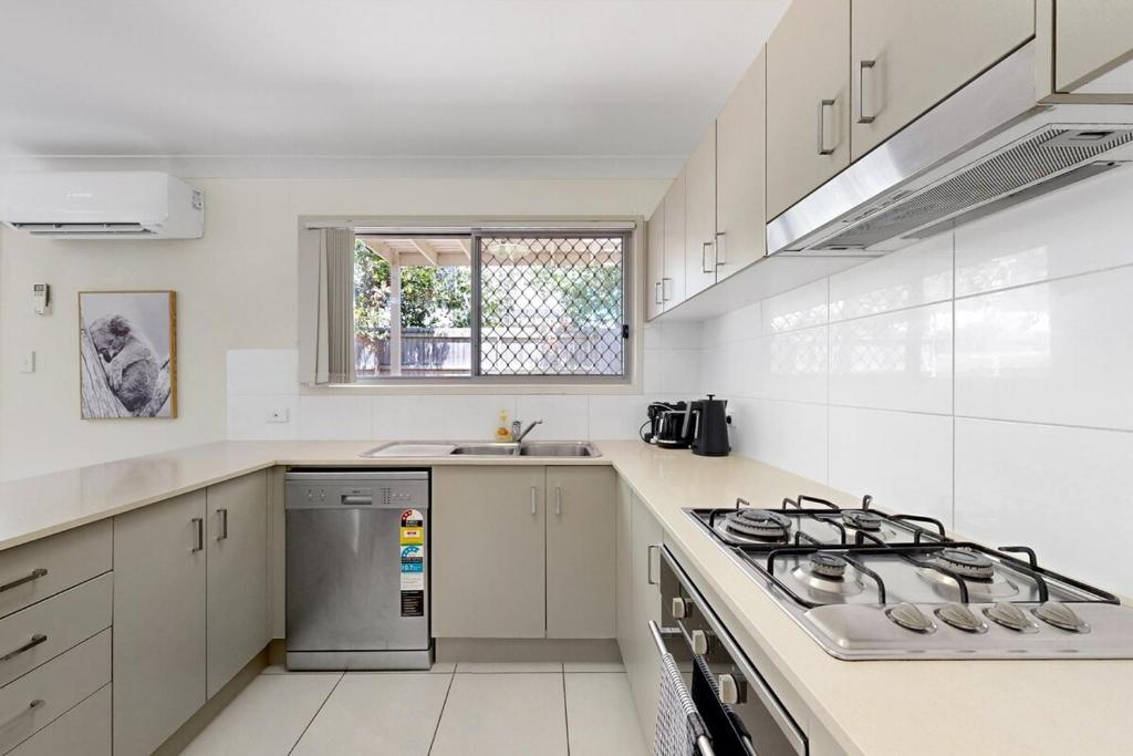 eine weiße Küche mit Herd und Spüle in der Unterkunft Mango Hill 3 Bedroom Family Accommodation in North Lakes