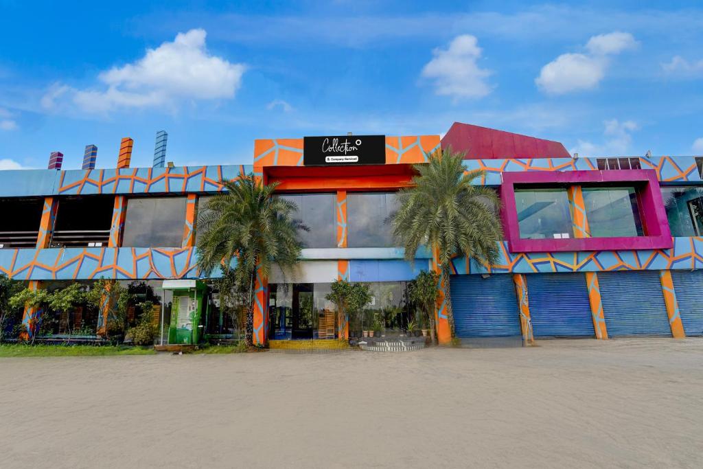 a building with palm trees in front of it at Collection O Sirkazhi Formerly Navagiraga Resort in Vaithīsvarankoil