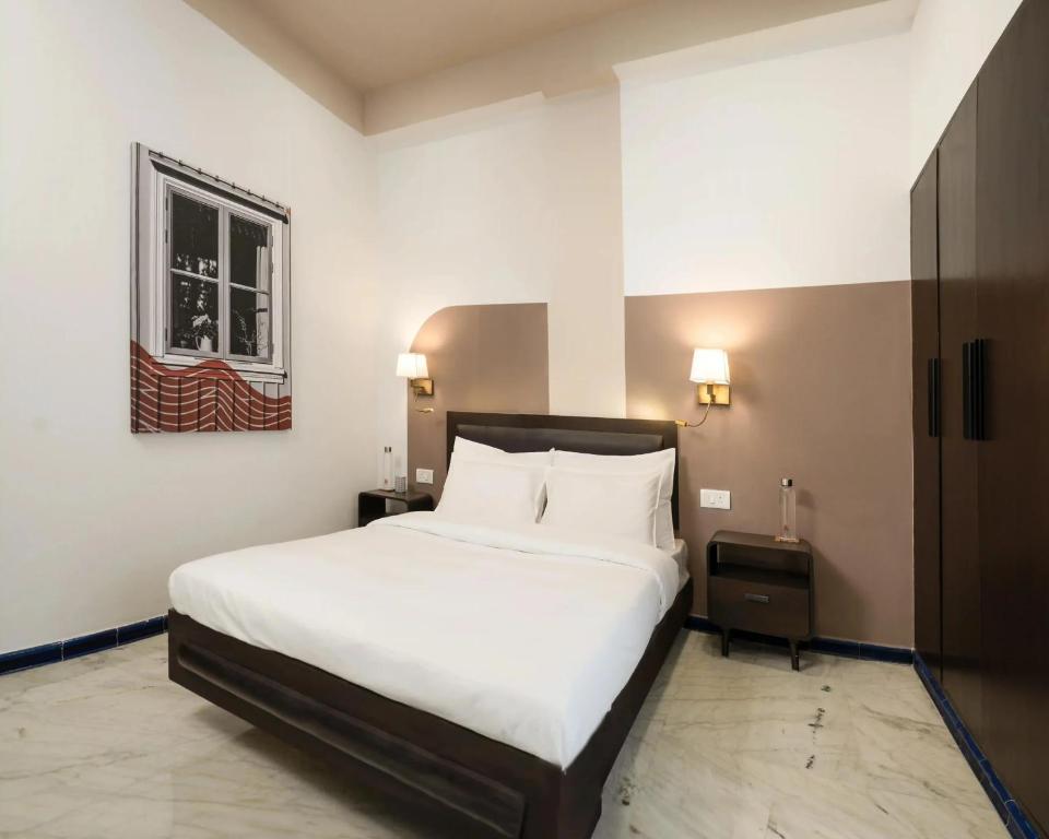 BedChambers Suites Near Sector 29, Gurgaon في جورجاون: غرفة نوم بها سرير أبيض كبير ونافذة