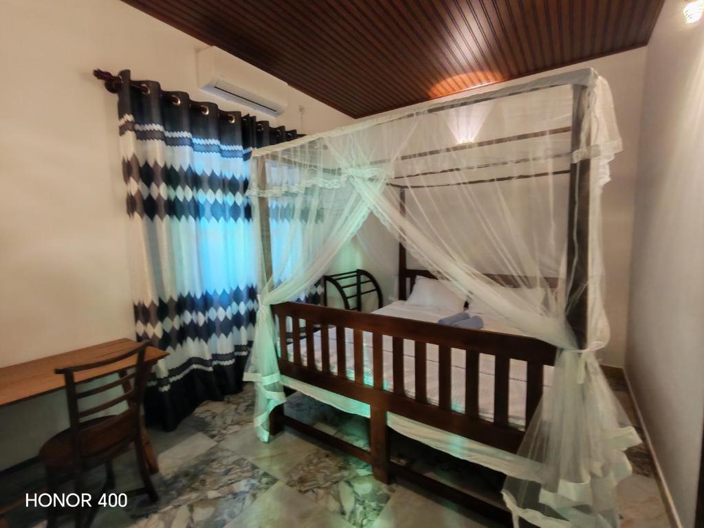 1 dormitorio con cama con dosel y mesa en Hilltop Haven, en Mirissa