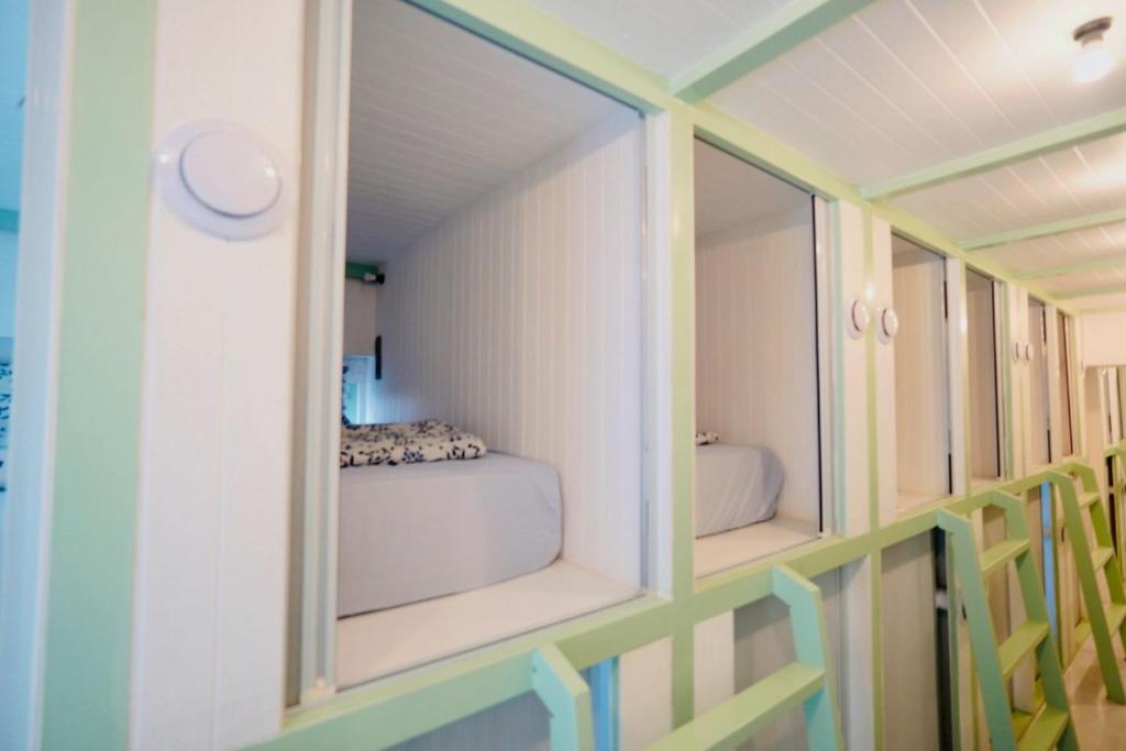 a small room with two windows and a bed in it at Easy Monday Capsule Hotel Bangkok in Bangkok