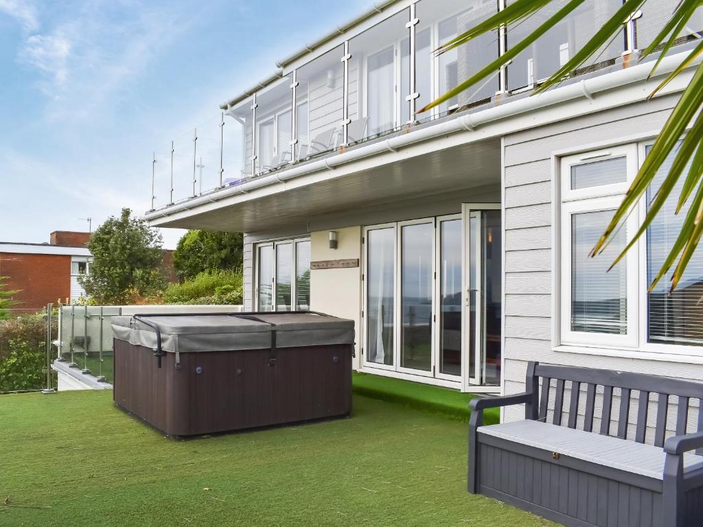 een huis met een bubbelbad en een bankje op het gazon bij Oceans Away - Uk48571 in Woolacombe