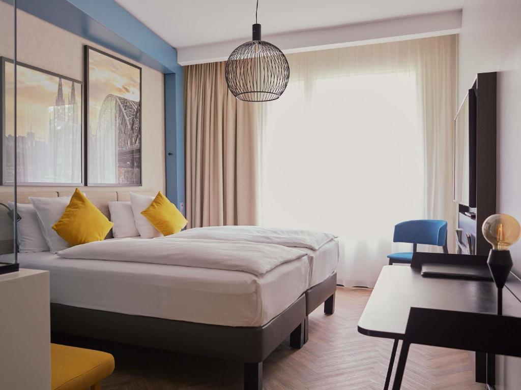 a bedroom with a bed and a desk and a window at Hotel Mondial am Dom Cologne MGallery in Cologne