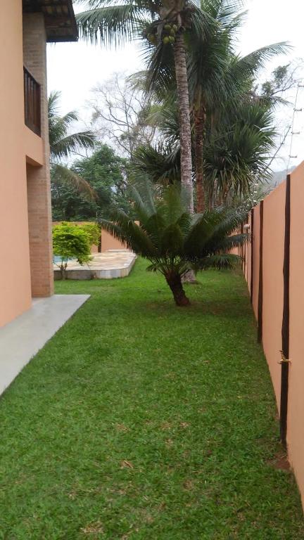 a green yard with a palm tree next to a building at Refugio Massaguaçu in Caraguatatuba