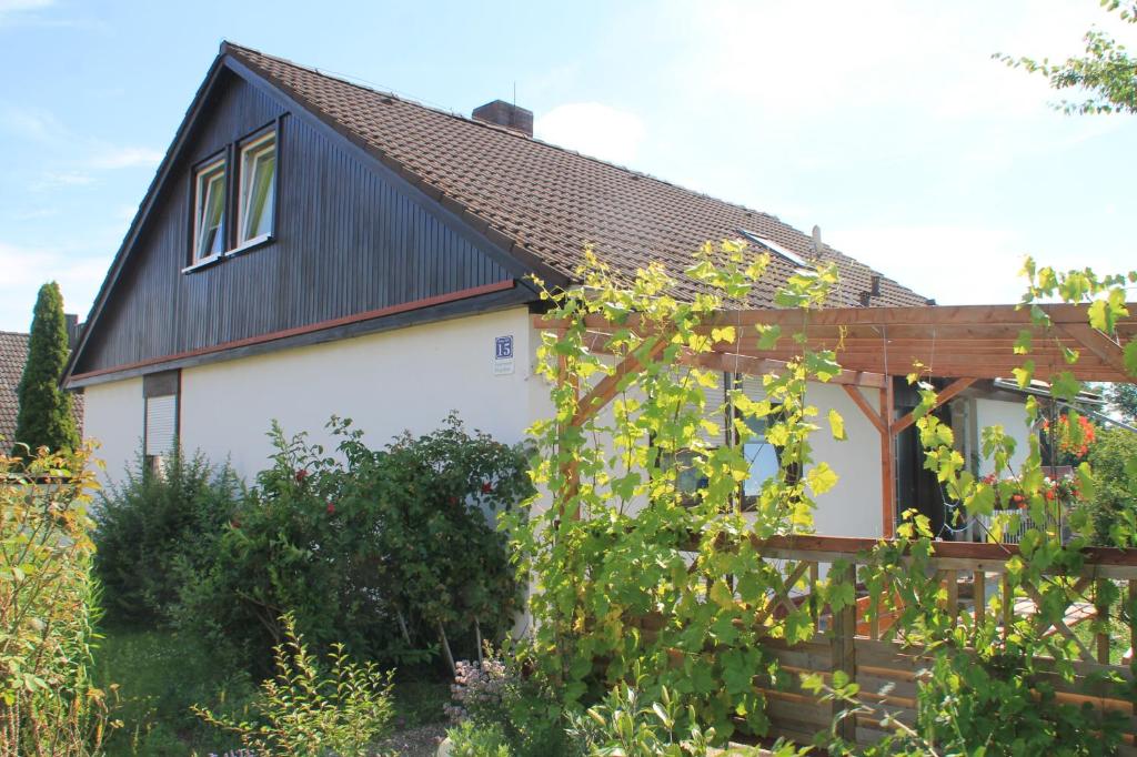 ein Haus mit einem schwarzen Dach und einem Zaun in der Unterkunft Apartment Bergblick Bischberg bei Bamberg in Bischberg