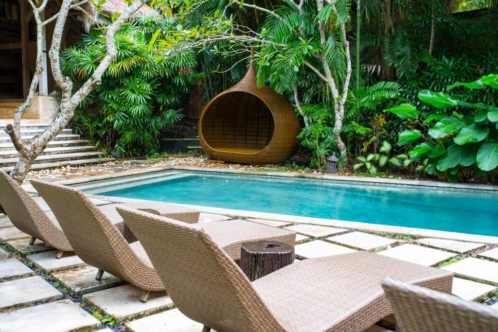 a swimming pool with chairs and a table and a swimming pool at Nomadic Resort Bali in Canggu