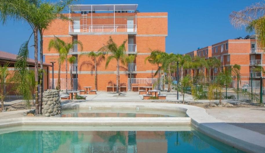 a swimming pool in front of a brick building at Departamento Villas Doradas in Santa Cruz Huatulco