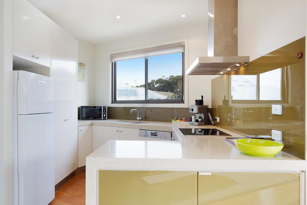 a white kitchen with a yellow bowl on a counter at Rolling Waves 1 in Merimbula