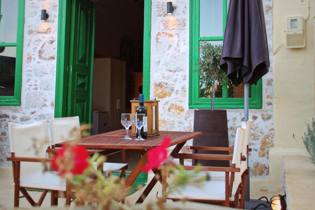 a wooden table and chairs with a bottle and glasses at Hypate, traditional island cottage in Halki