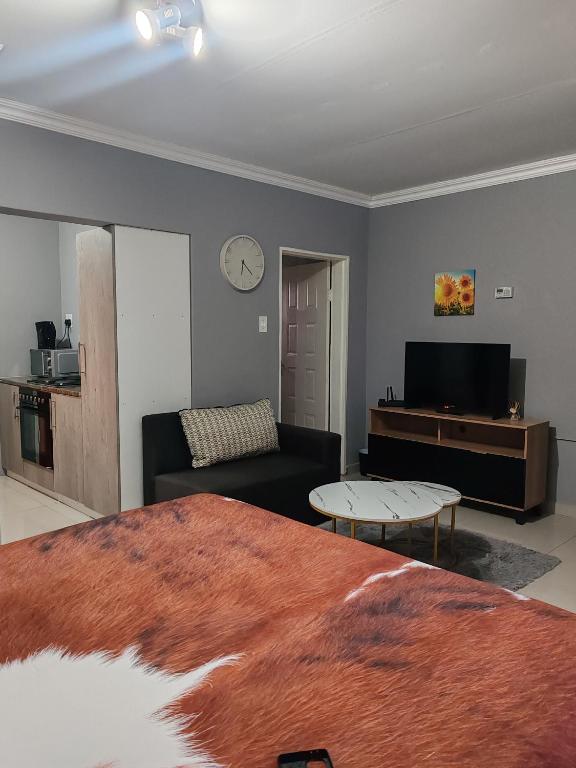 a living room with a bed and a couch at Ekukhanyeni Guest house in Kwaluseni