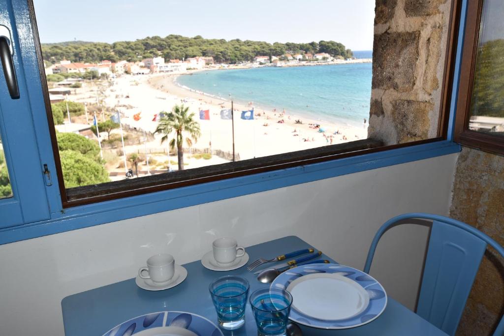 einen Tisch mit Blick auf den Strand von einem Fenster aus in der Unterkunft Le Provence Plage in La Seyne-sur-Mer