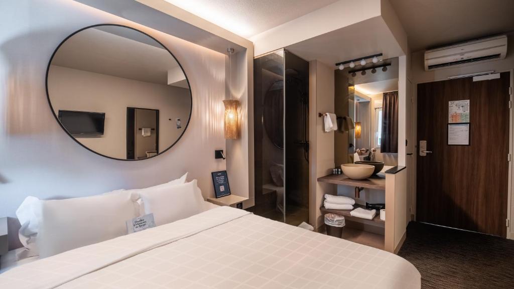 Hôtel Kyriad Brive Ouest في بريف لا غايلارد: غرفة نوم بها سرير أبيض كبير ومرآة