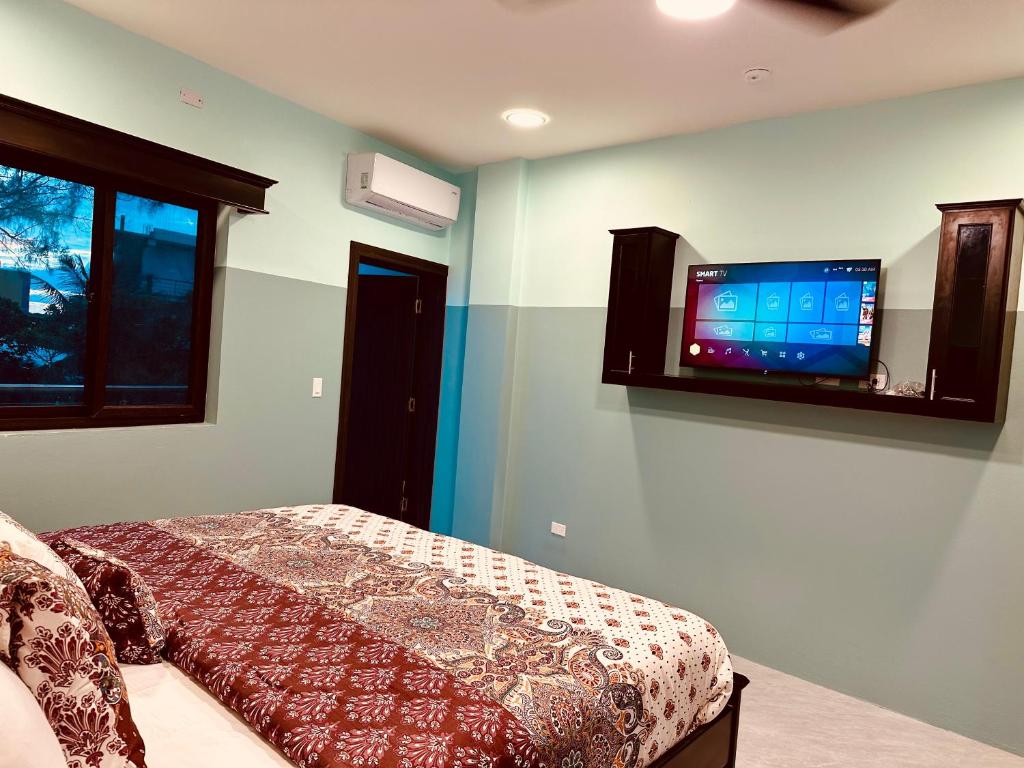 a bedroom with a bed and a flat screen tv on the wall at Hotel Sea Queen Suite & Golf Cart Rental in San Pedro