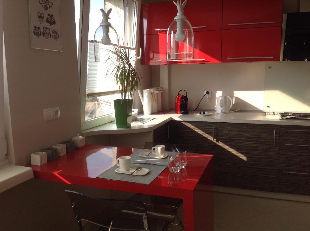 a kitchen with red cabinets and a red table at AS Apartment Lodz in Łódź