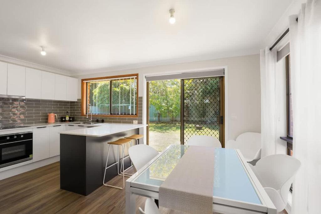 een keuken met een glazen tafel en witte apparaten bij Aqua on Achilles in Nelson Bay