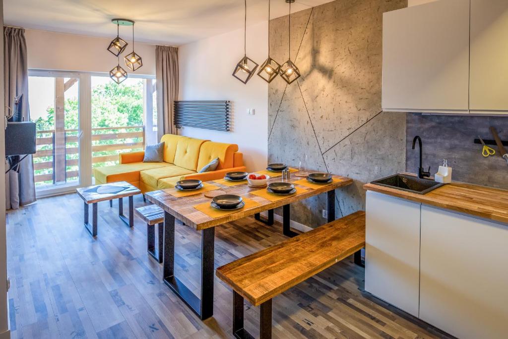 a kitchen and living room with a table and a couch at Apartament Widokowy Karpacz z garażem i widokiem na góry, blisko szlaki i centrum in Karpacz