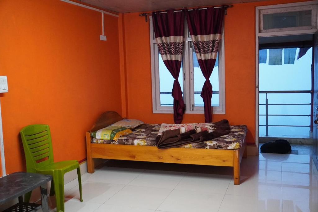 Cholo Ghure Ashi-Sillery Gaon Homestay في Pedong: غرفة نوم بجدران برتقالية وسرير ونافذة