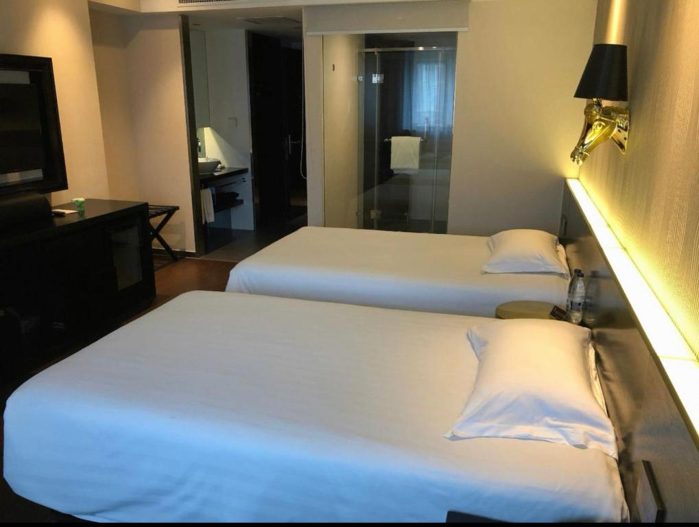 Giường trong phòng chung tại Orange Hotel Suzhou Xiangcheng Avenue Global Harbor