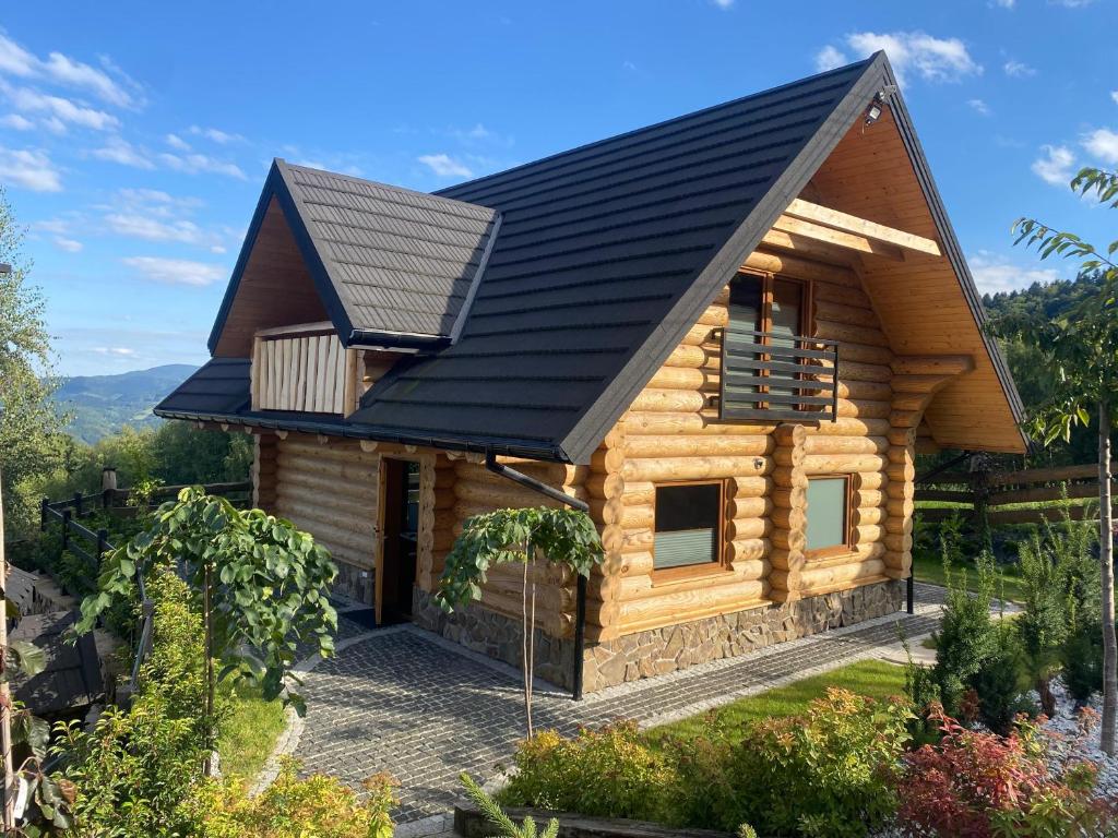 Bali domy RESTORT & SPA في Laskowa: كابينة خشب بسقف أسود